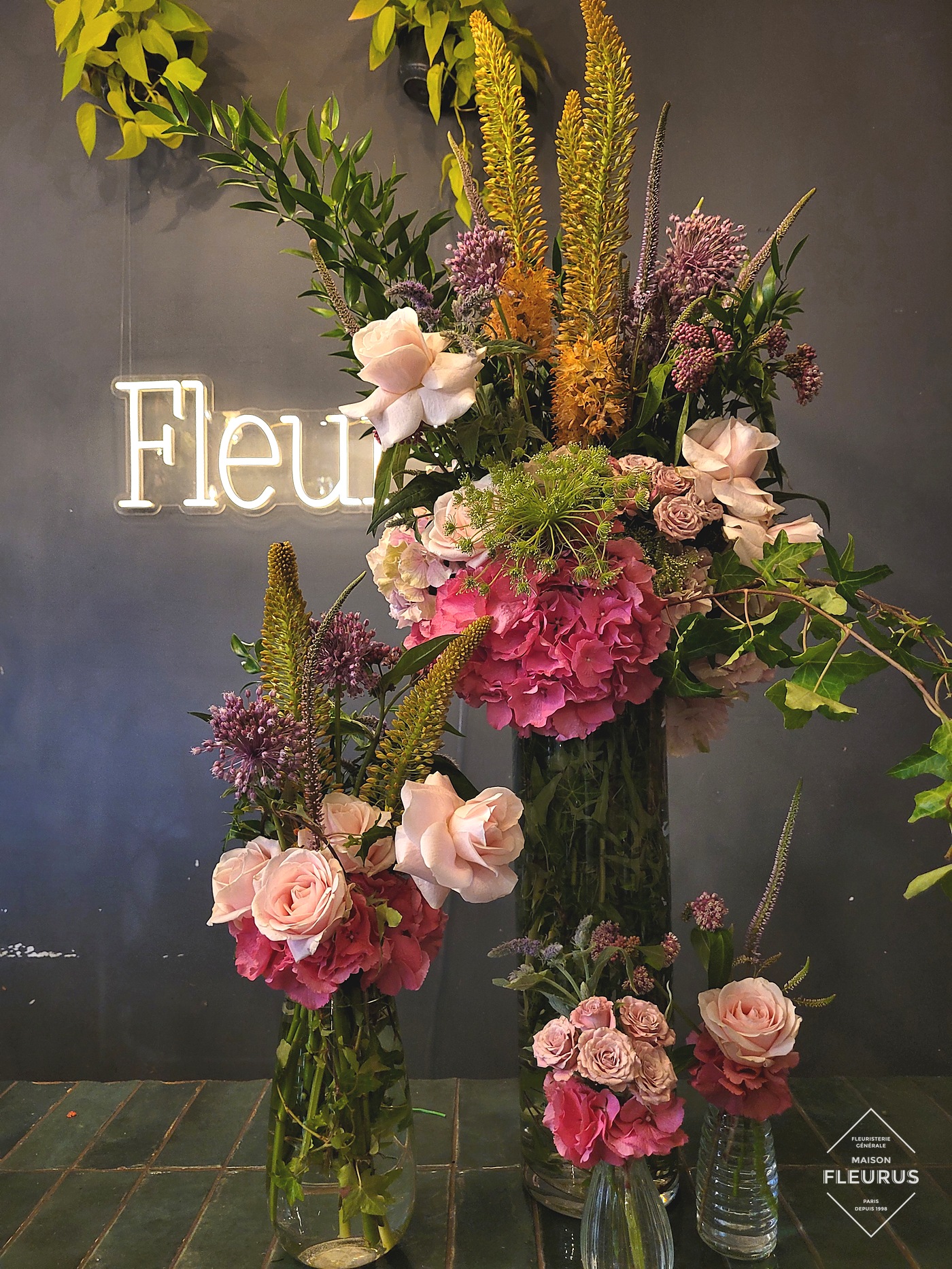 Bouquet de présentation Maison Fleurus, roses, hortensias roses, éremurus, devant l'enseigne Fleurs